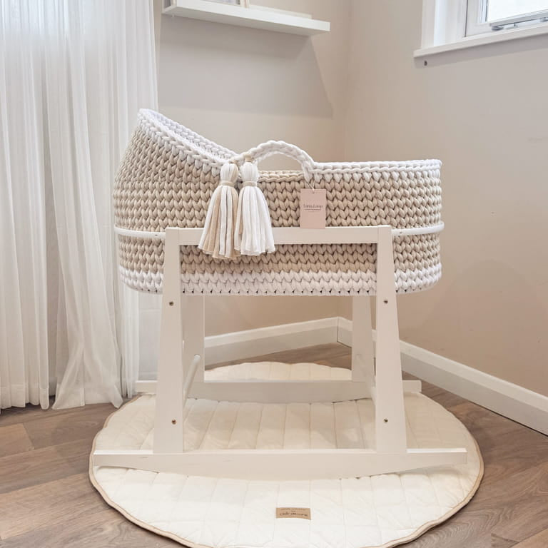 Hooded crochet Moses basket on a white rocking stand in a nursery